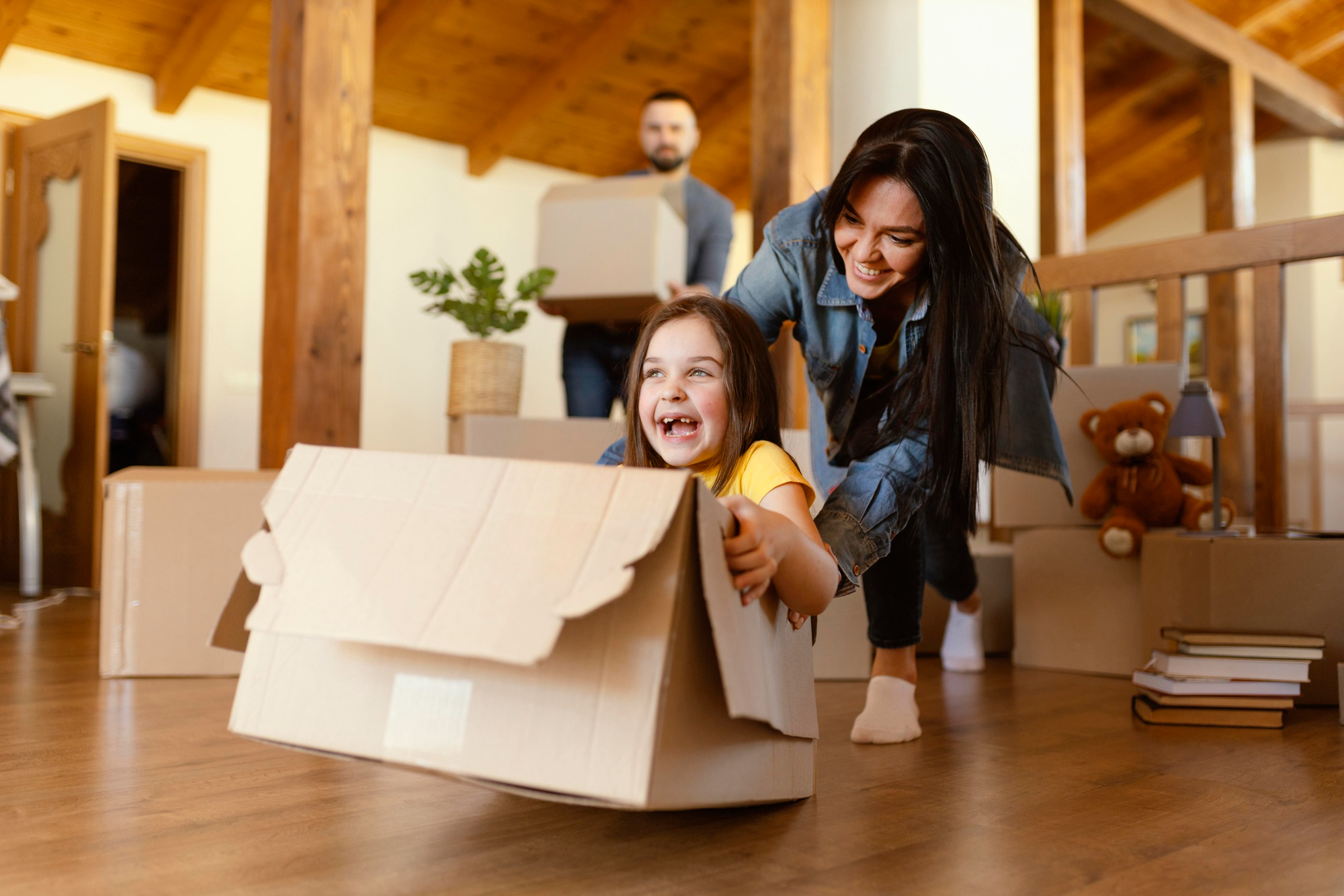 Happy family moving into a new home, with a smiling child playing in a cardboard box while parents unpack, symbolizing a fresh start and relief after selling their house