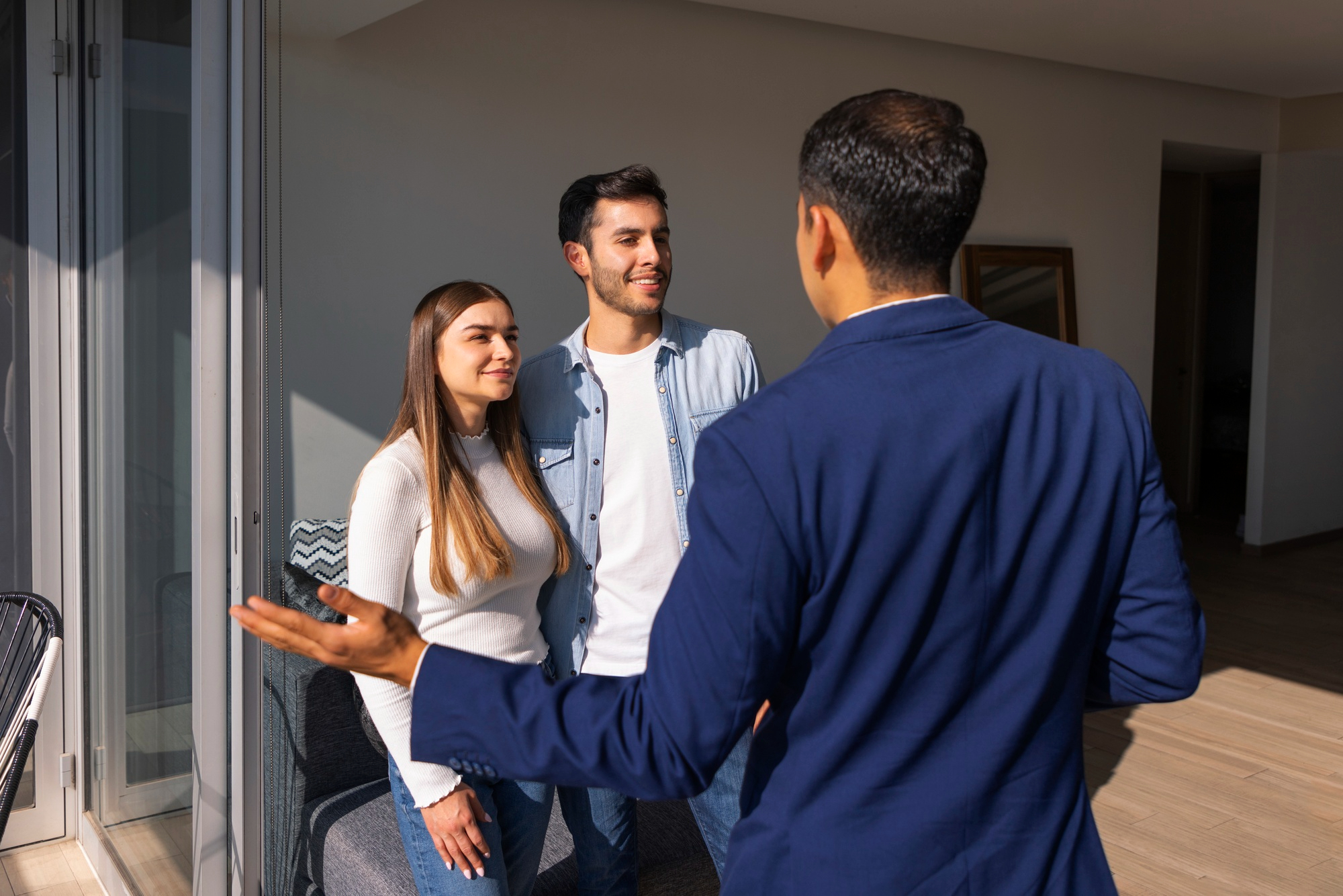 Real estate agent showing new property to happy couple inside modern apartment.