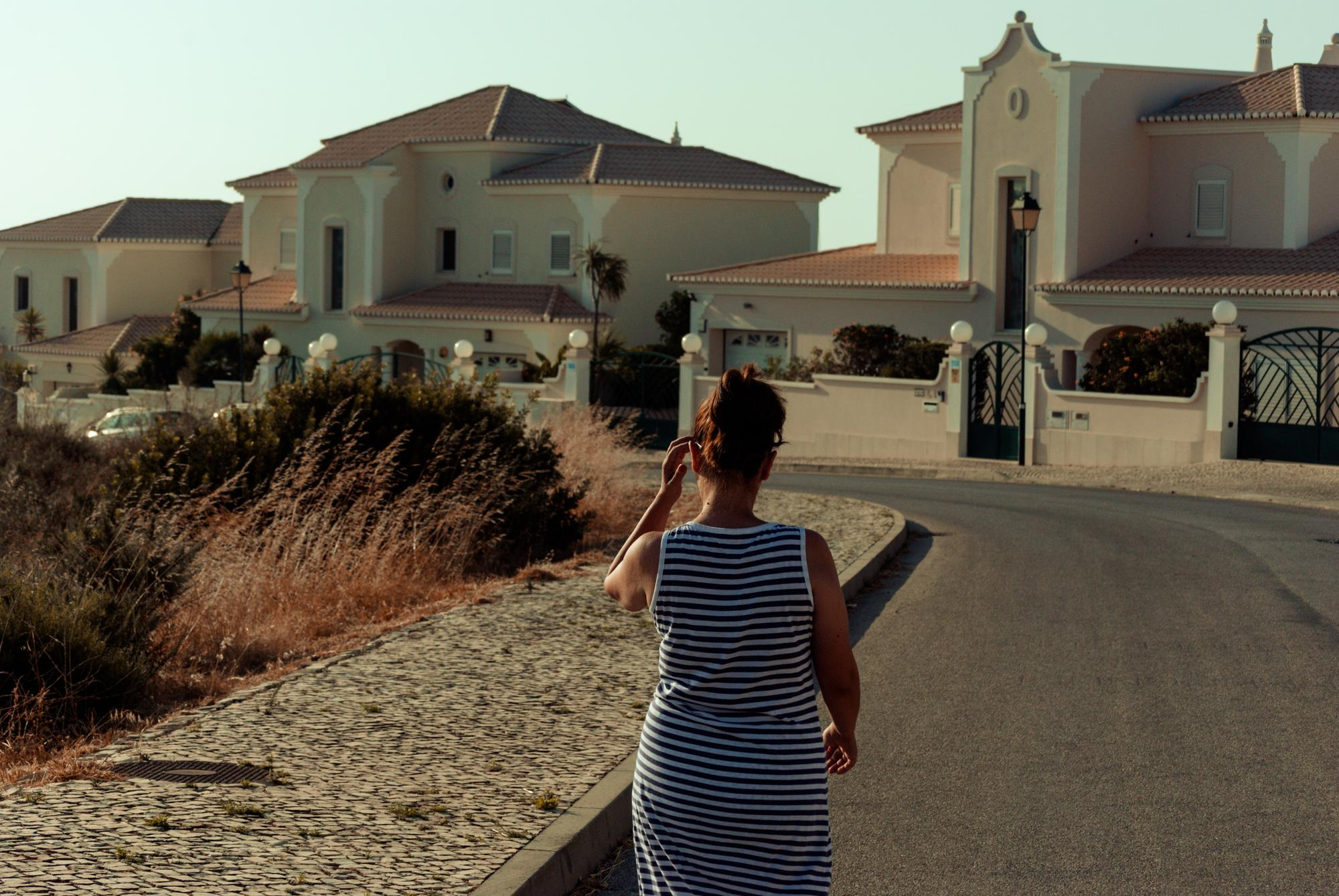 Woman walking through luxury residential neighborhood with modern houses and elegant architecture